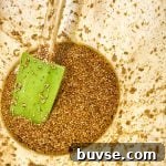 The marinade, with soy sauce and sesame seeds in a bowl with a green spatula.