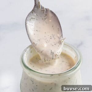 A small weck jar with a creamy sauce with a spoon scooping some out.