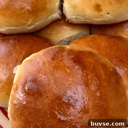 Homemade sandwich rolls stacked on a baking mat