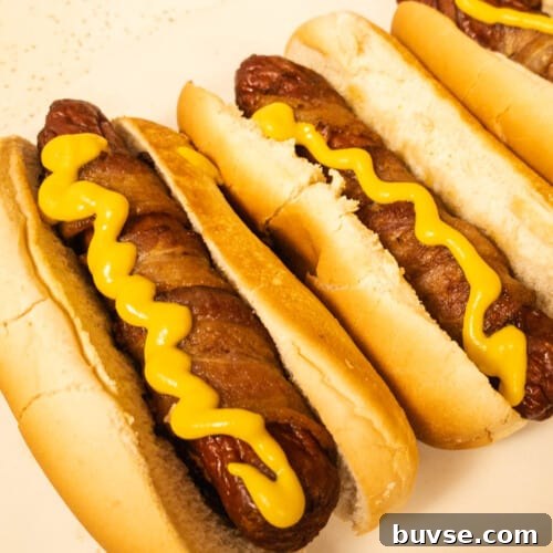 Bacon wrapped hot dog ready to eat with some yellow mustard