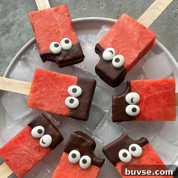 Rectangular watermelon popsicles on sticks, partially dipped in chocolate and decorated with candy eyes, are arranged on a plate of ice. One popsicle has a small bite taken out—making these fun bites perfect for healthy food recipes.
