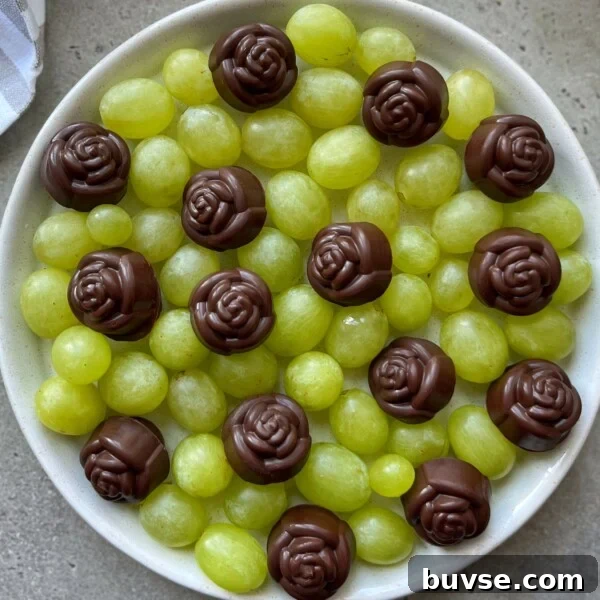 A white bowl filled with green grapes, topped with several chocolate candies shaped like roses, arranged evenly on the surface—perfect for health-conscious bites and creative food recipes.