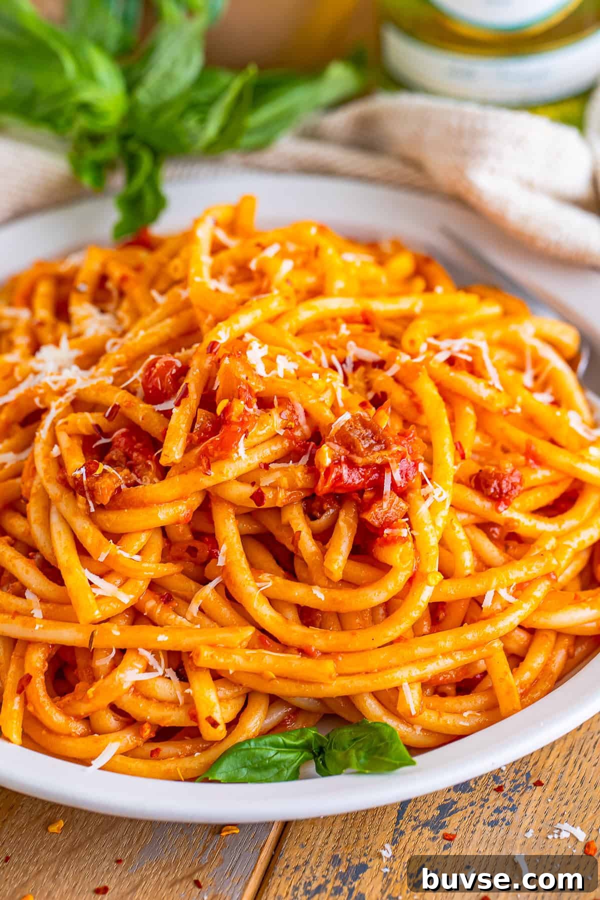 Amatriciana Pasta (Bucatini) - Authentic Italian Recipe 2 A white bowl of Pasta Amatriciana with bucatini coated in tomato sauce, crispy guanciale, and grated pecorino romano.
