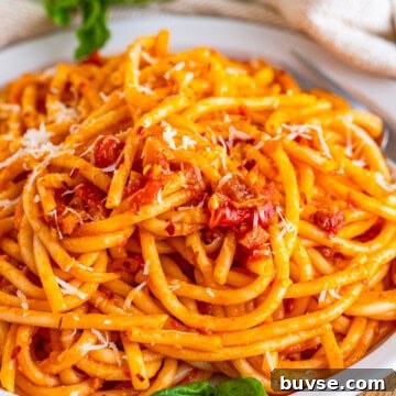 Amatriciana Pasta (Bucatini) - Authentic Italian Recipe 11 A white bowl of Pasta Amatriciana with bucatini coated in tomato sauce, crispy guanciale, and grated pecorino romano.