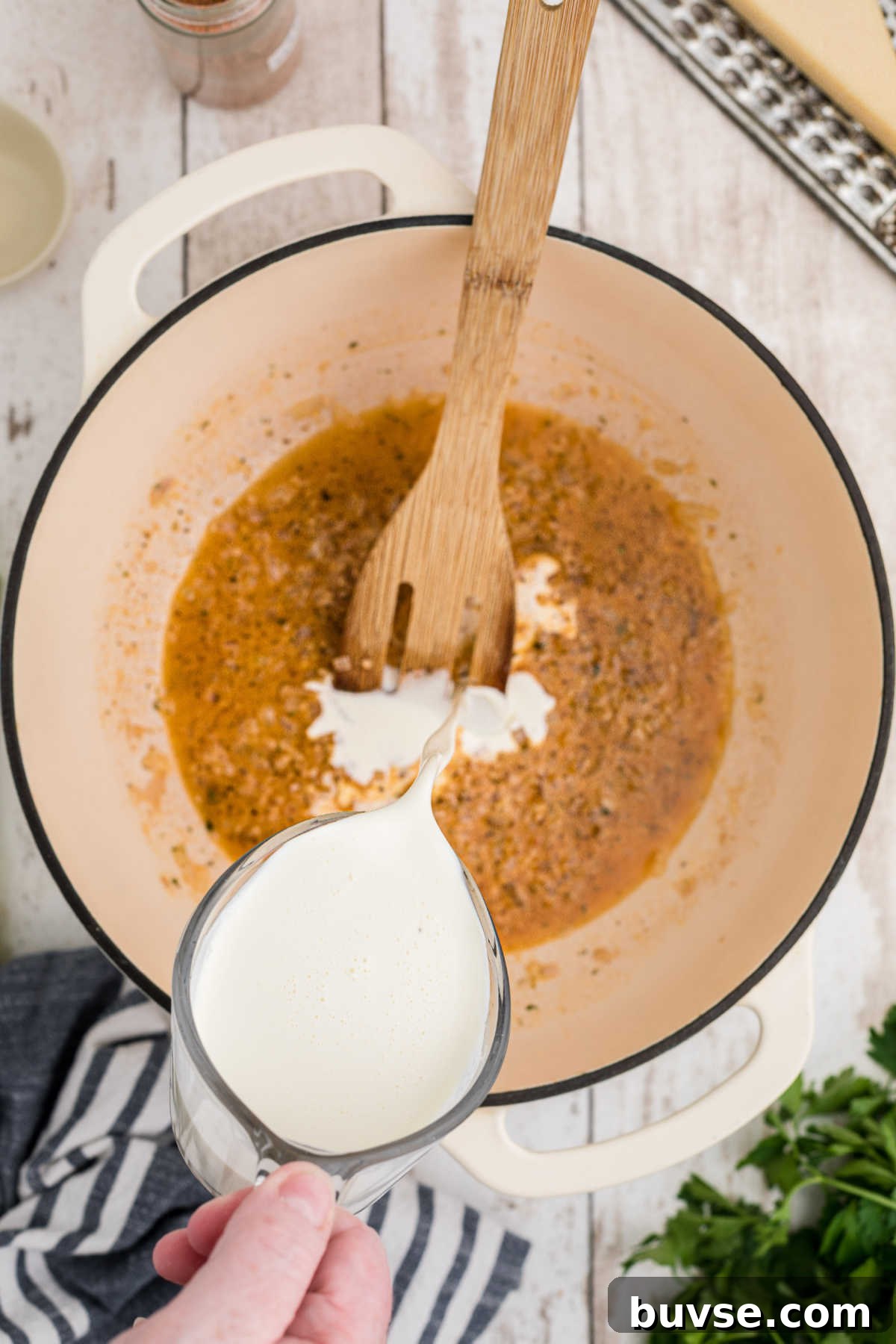 Cream being poured into a pot with shallots.