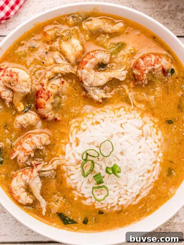 Bowl of crawfish etouffee with rice scoop in the middle.