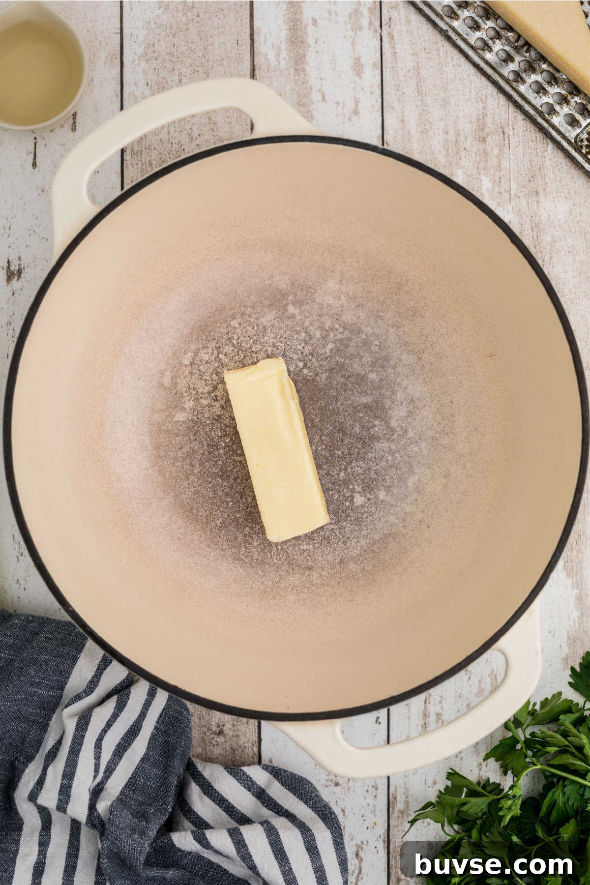 A large Dutch Oven with a stick of butter.