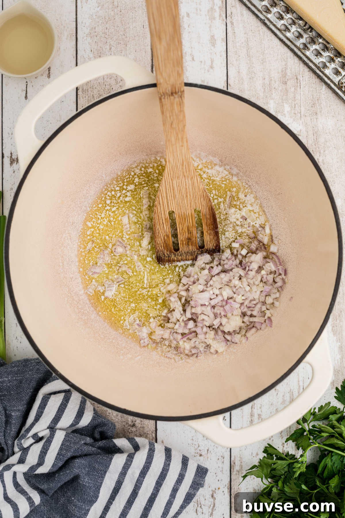 A large Dutch Oven with butter and chopped shallots.