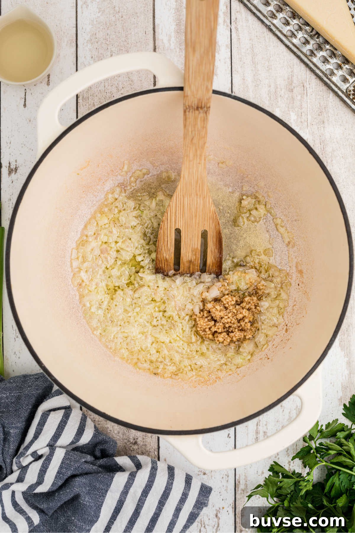 Garlic being added to a large pot with shallots and butter.