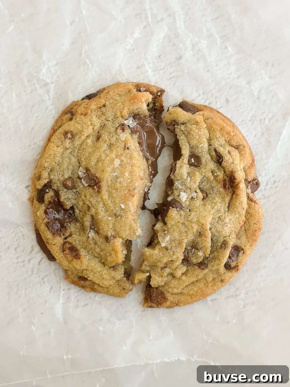 a close up of a fresh cookie with melty chocolate oozing out.