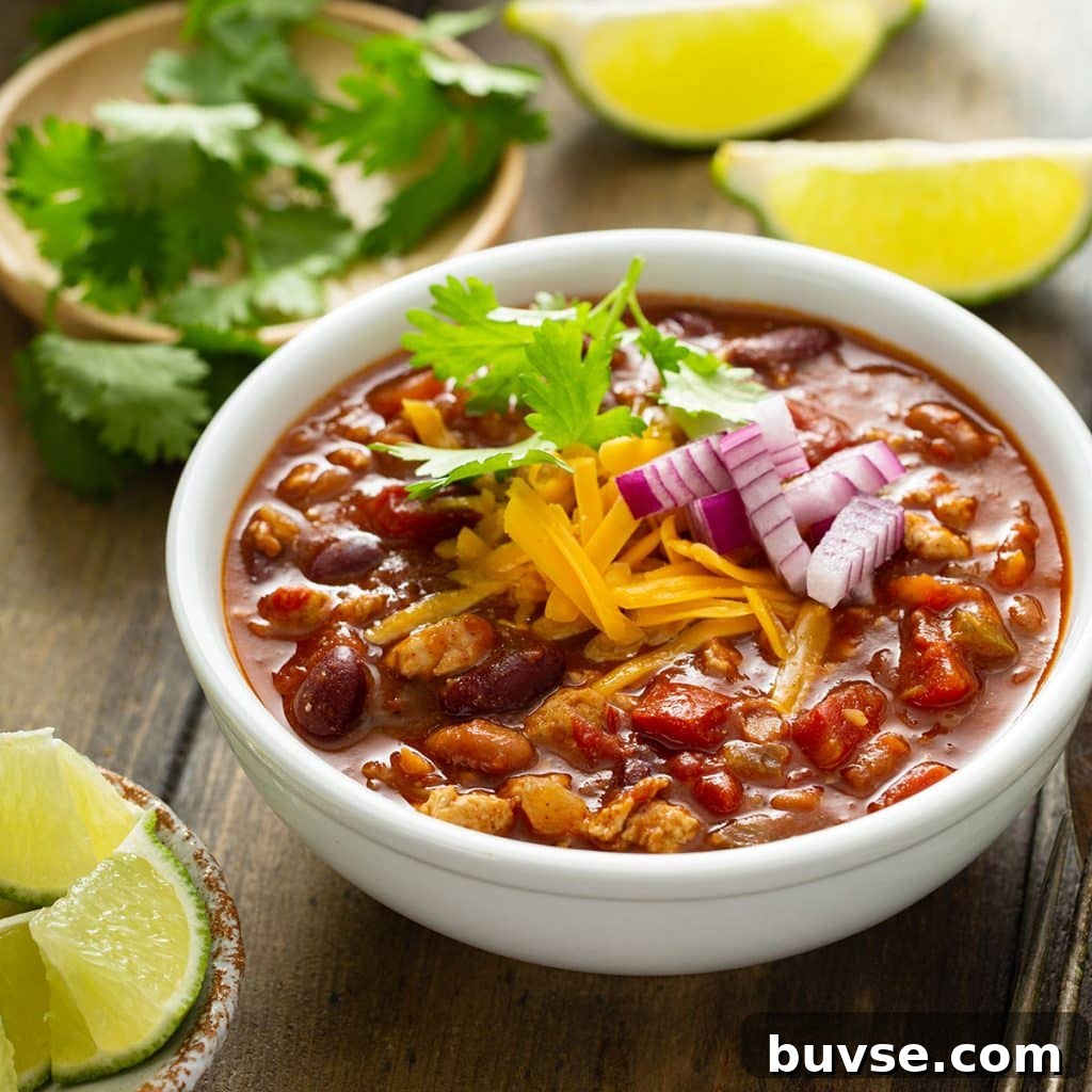 Cook Once, Eat Twice: Budget Recipes for Delicious Leftovers 13 Turkey chili in a white bowl garnished with chopped red onion, shredded cheese and cilantro