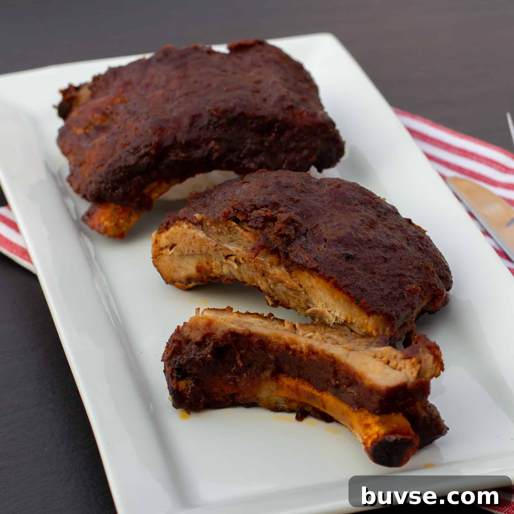 Slow braised ribs with rub and bourbon bbq sauce recipe. Cook in the oven or crock pot / slow cooker. Meat is fall off the bone tender.