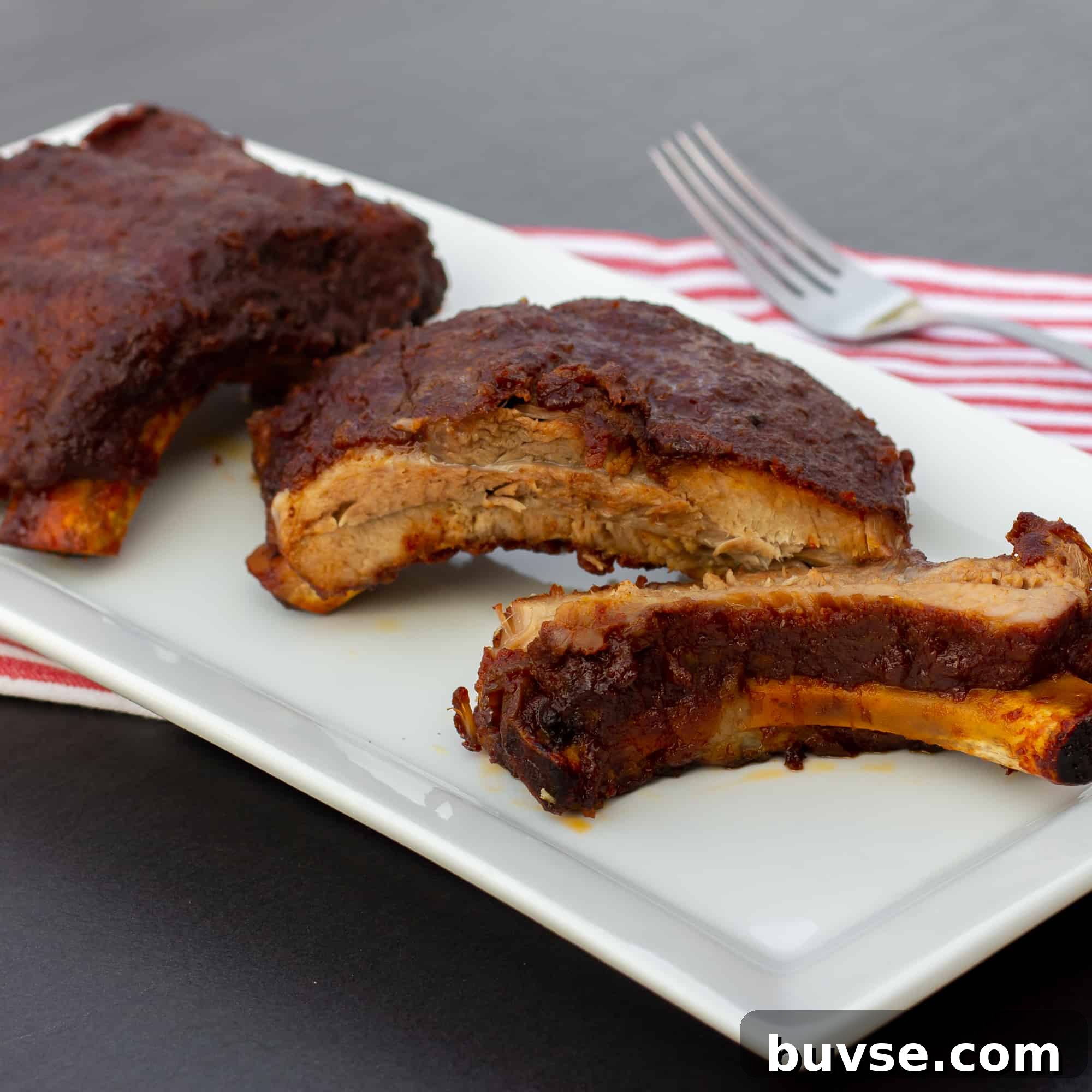 Slow braised ribs with rub and bourbon bbq sauce recipe. Cook in the oven or crock pot / slow cooker. Meat is fall off the bone tender.