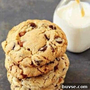 A stack of turtle cookies in front of a glass of milk on a stone surface