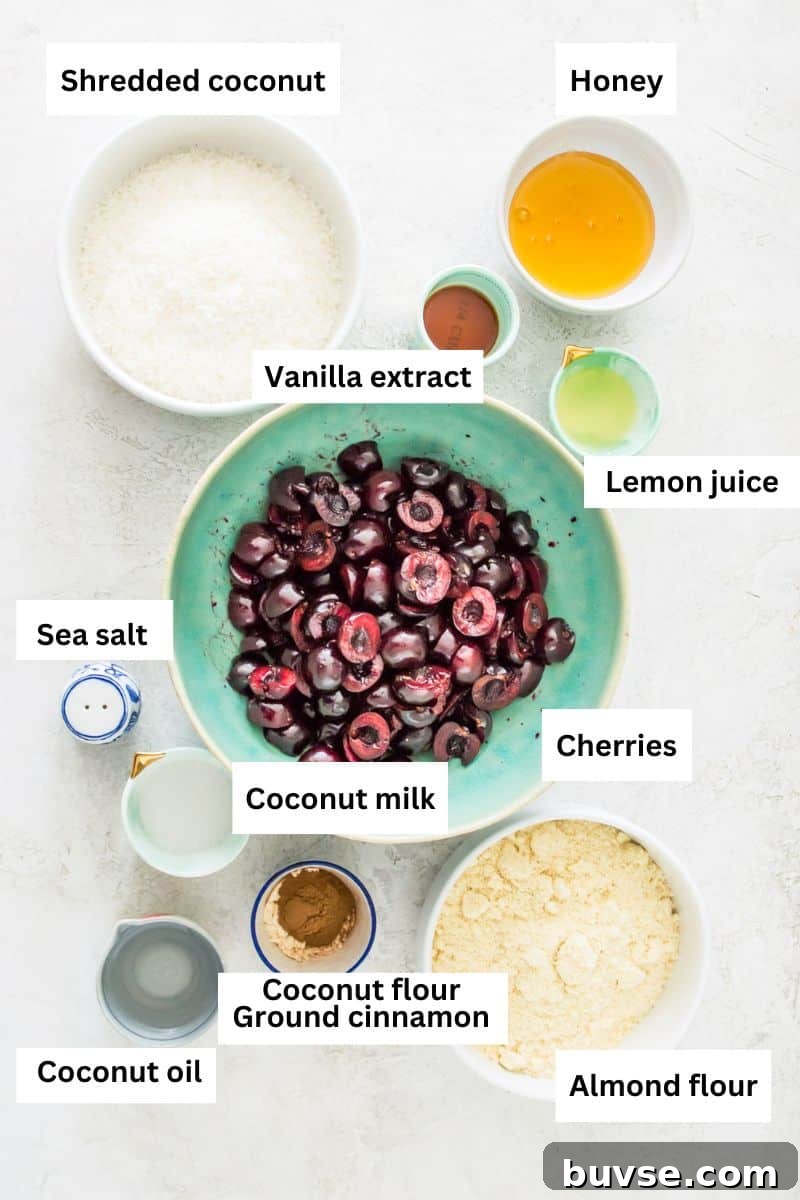 The ingredients needed to make a paleo cherry crisp separated into bowls including fresh cherries, almond flour, shredded coconut, honey and lemon juice.