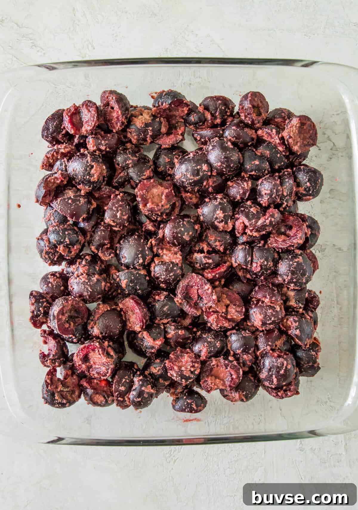 A glass baking dish with chopped cherries in it.