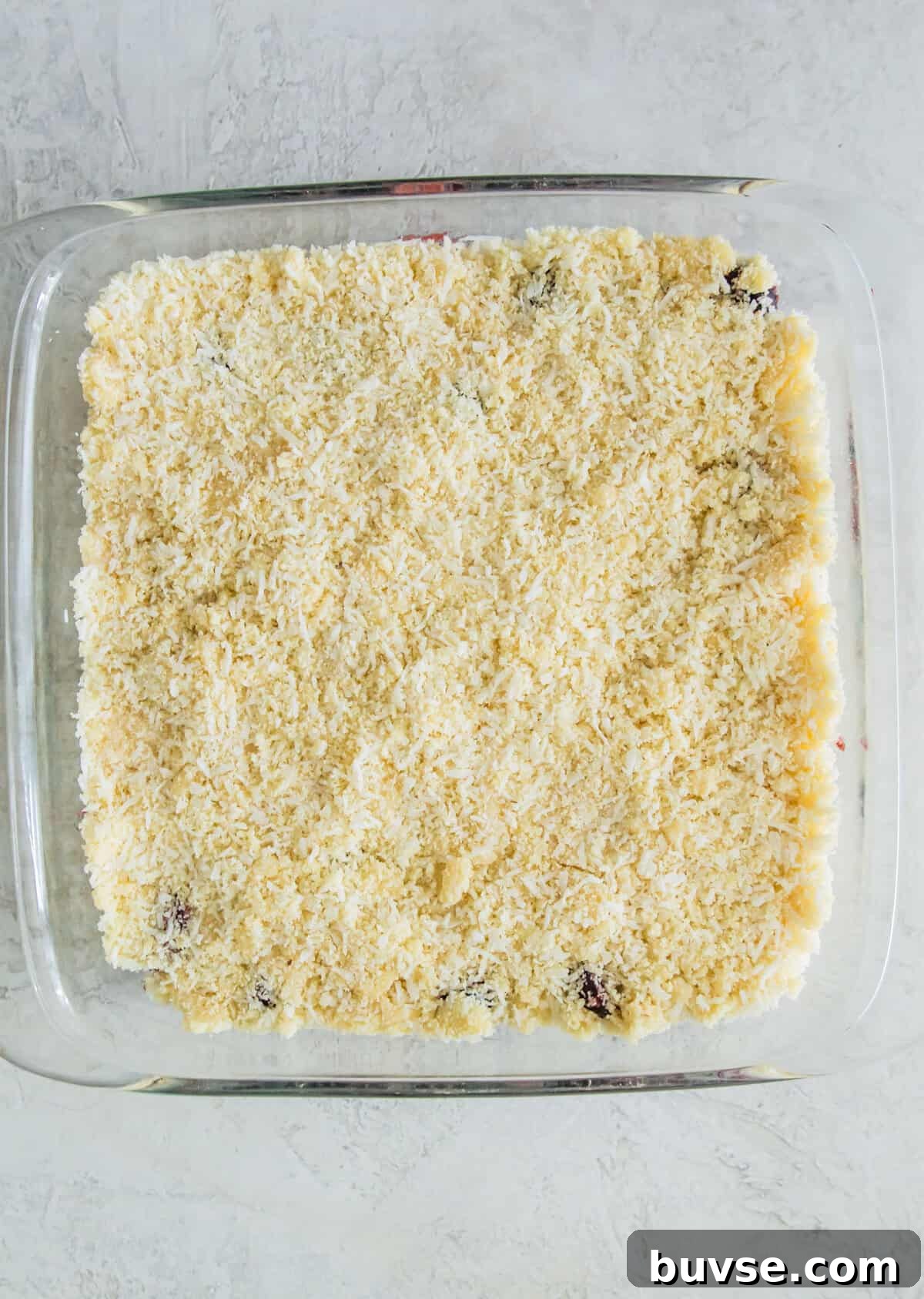 A square glass baking dish with a layer of almond flour and shredded coconut in it.