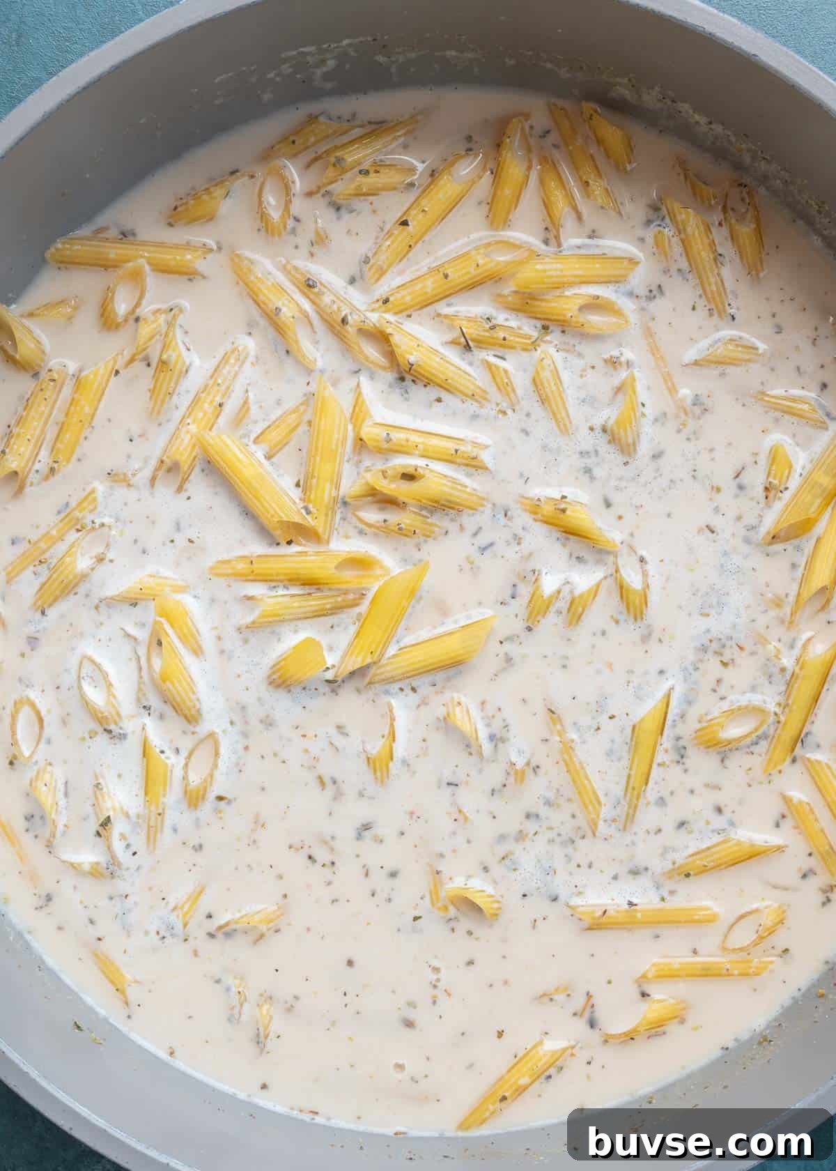 chicken and uncooked pasta in skillet