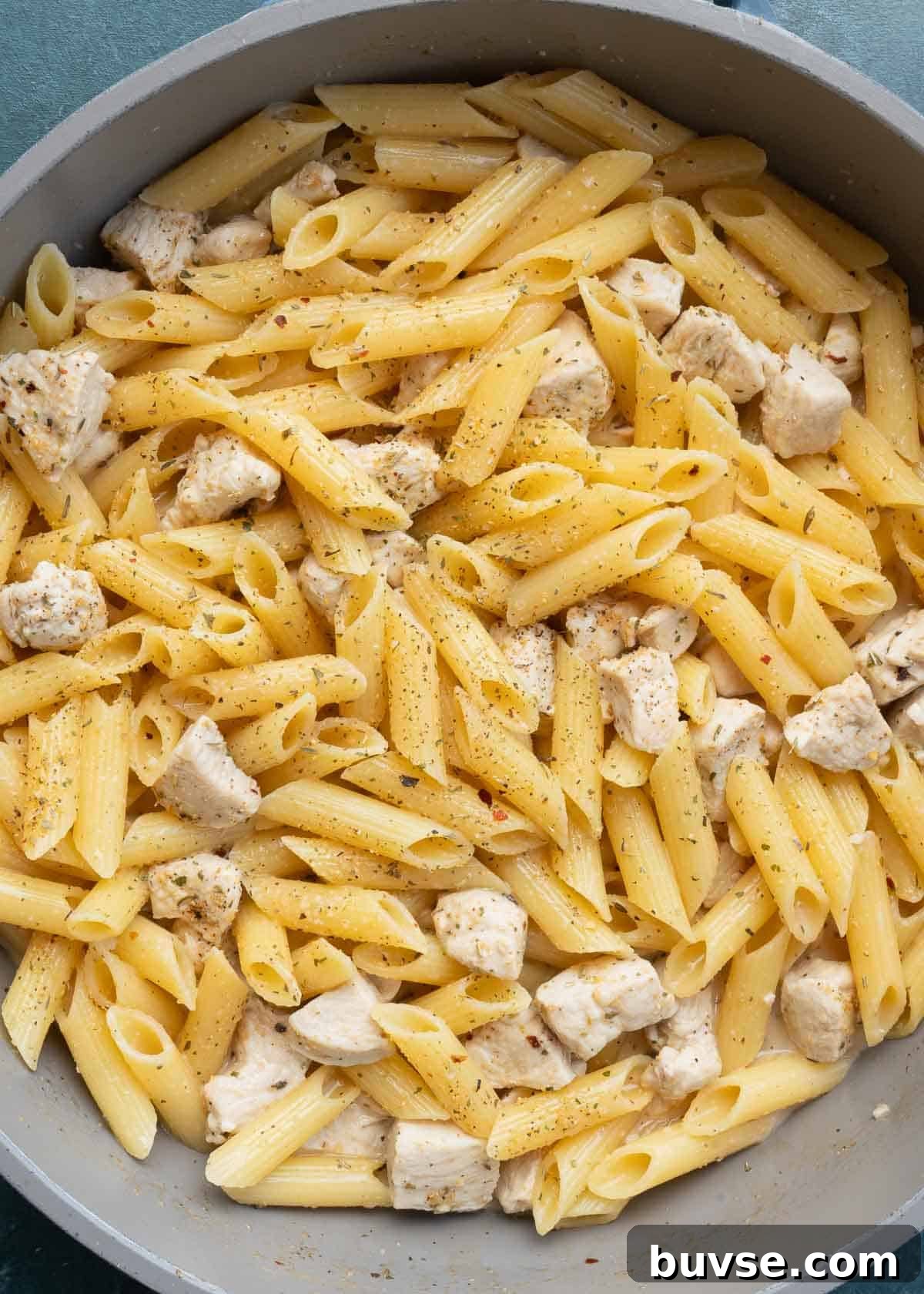 cooked penne and chicken in skillet