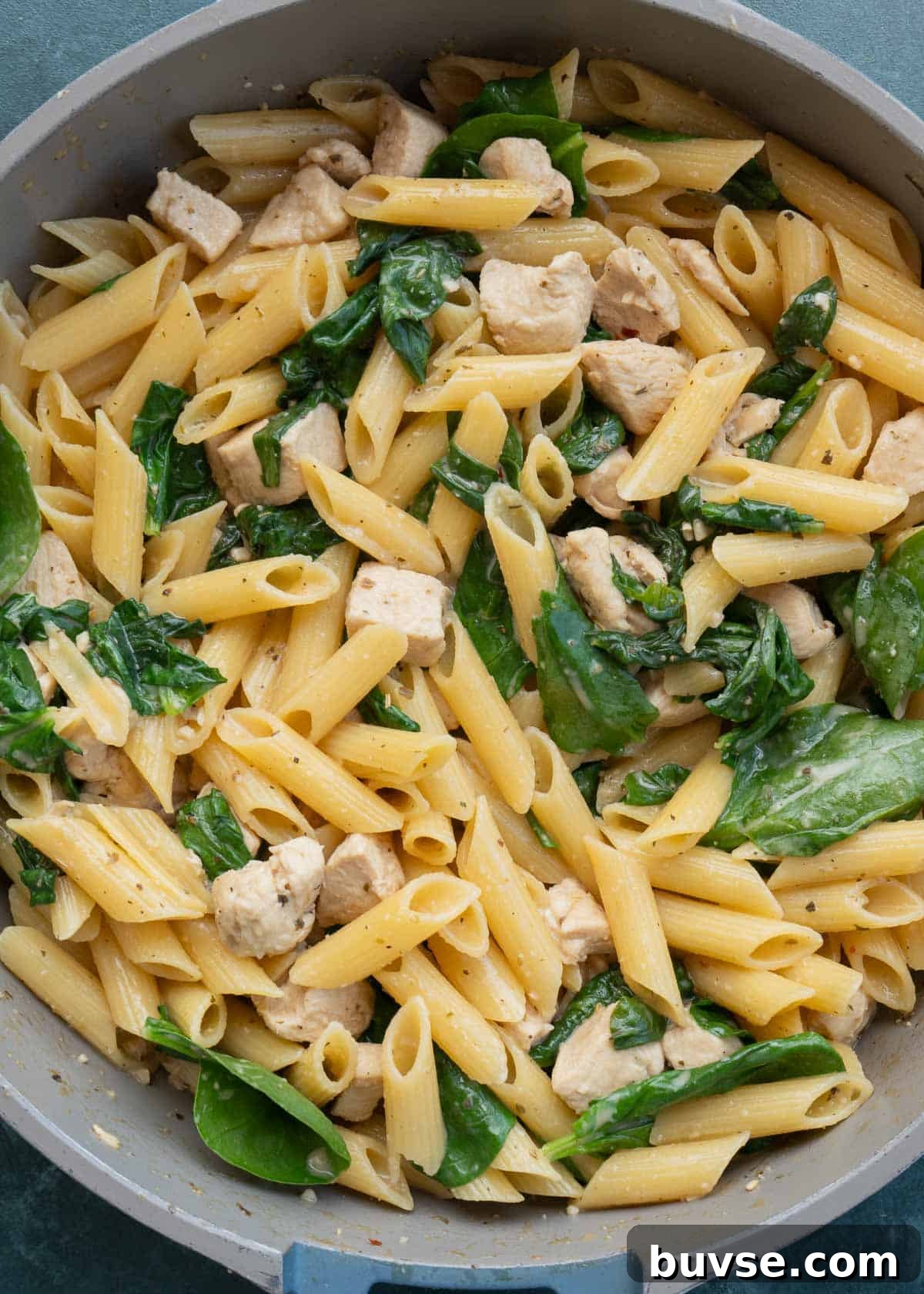 cooked spinach, pasta and chicken in skillet