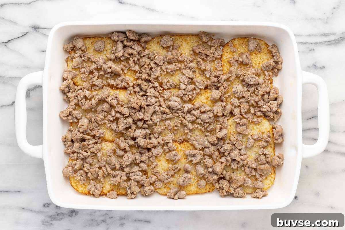 Cheesy Sausage Breakfast Casserole with Hash Browns 6 Cooked hash browns in a pan with cooked sausage.