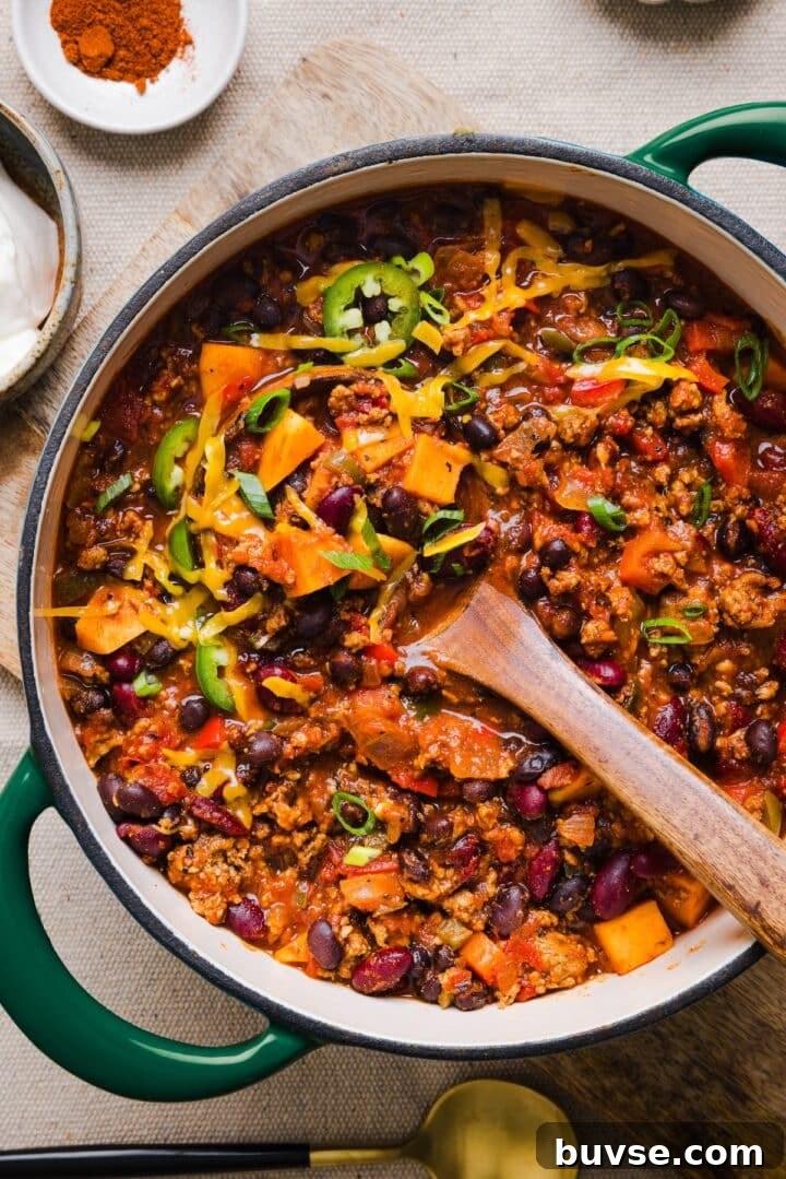 Hearty Sweet Potato Turkey Chili Recipe 2 Healthy sweet potato turkey chili in a large pot, topped with shredded cheddar and green onions.