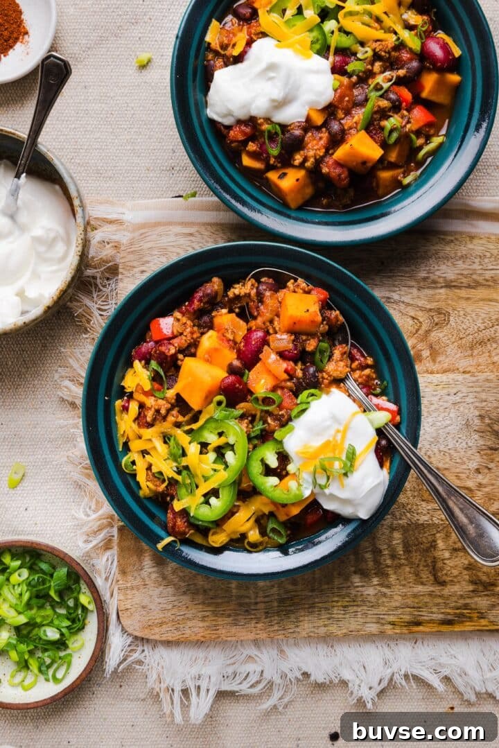 Hearty Sweet Potato Turkey Chili Recipe 7 Turkey chili in bowls on a wooden table.