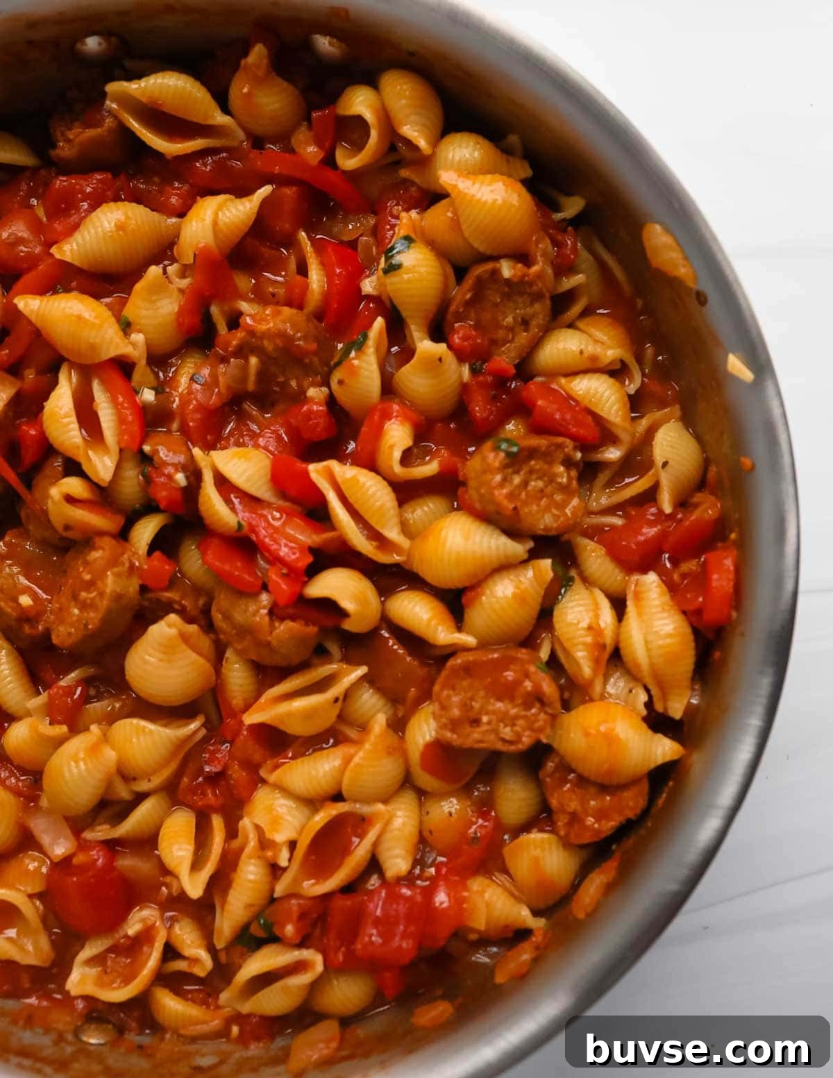 Creamy Vegan Cajun Pasta with Smoky Vegan Sausage 2 Cooked pasta in a pan with tomatoes, sausages, and sauce.