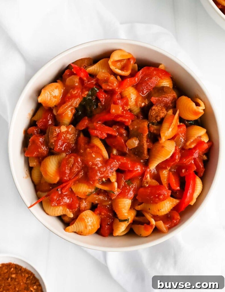 Creamy Vegan Cajun Pasta with Smoky Vegan Sausage 4 A white bowl with pasta, sauce, and sausage inside.