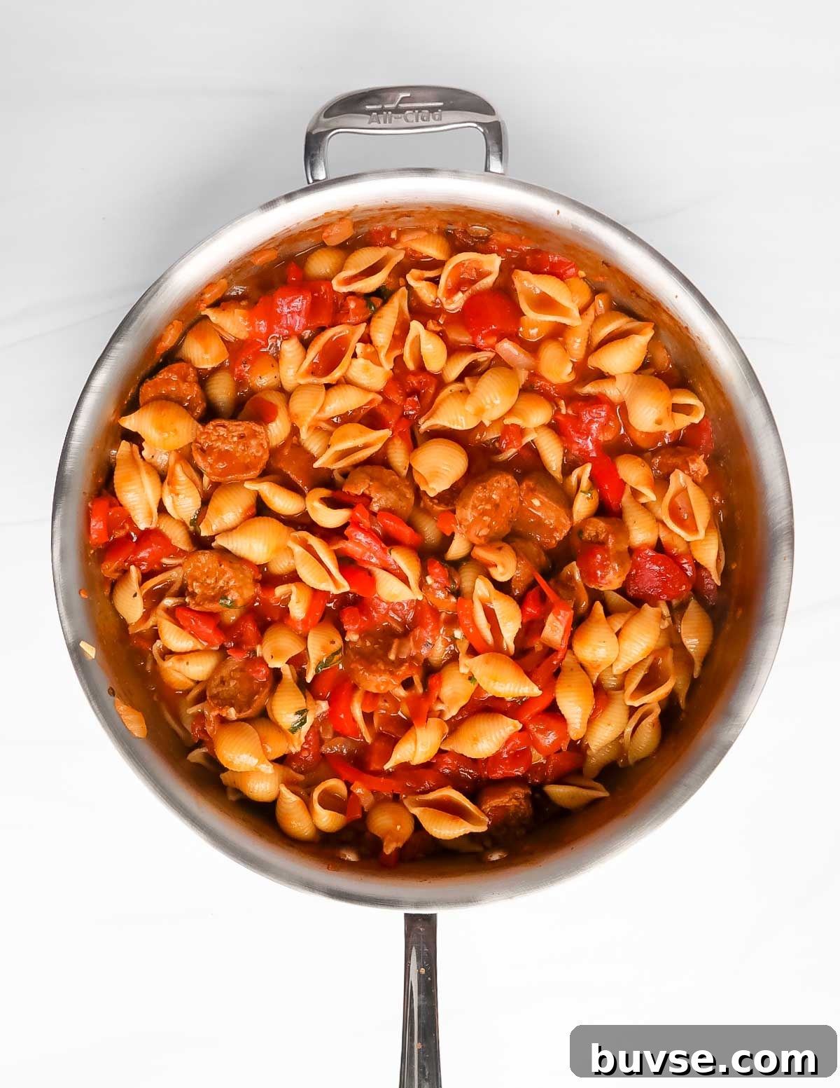 Creamy Vegan Cajun Pasta with Smoky Vegan Sausage 6 An overhead image of pasta in a large silver pan with sausages, tomatoes, peppers, and sauce.