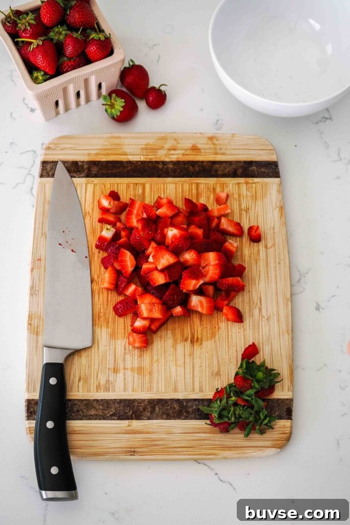 Diced strawberries on a wooden cutting board.