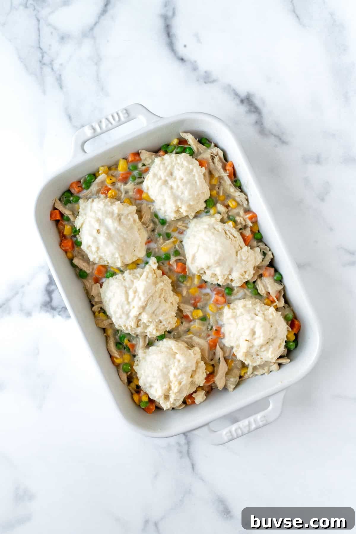 Chicken Pot Pie with Biscuits in a white casserole dish ready to bake.