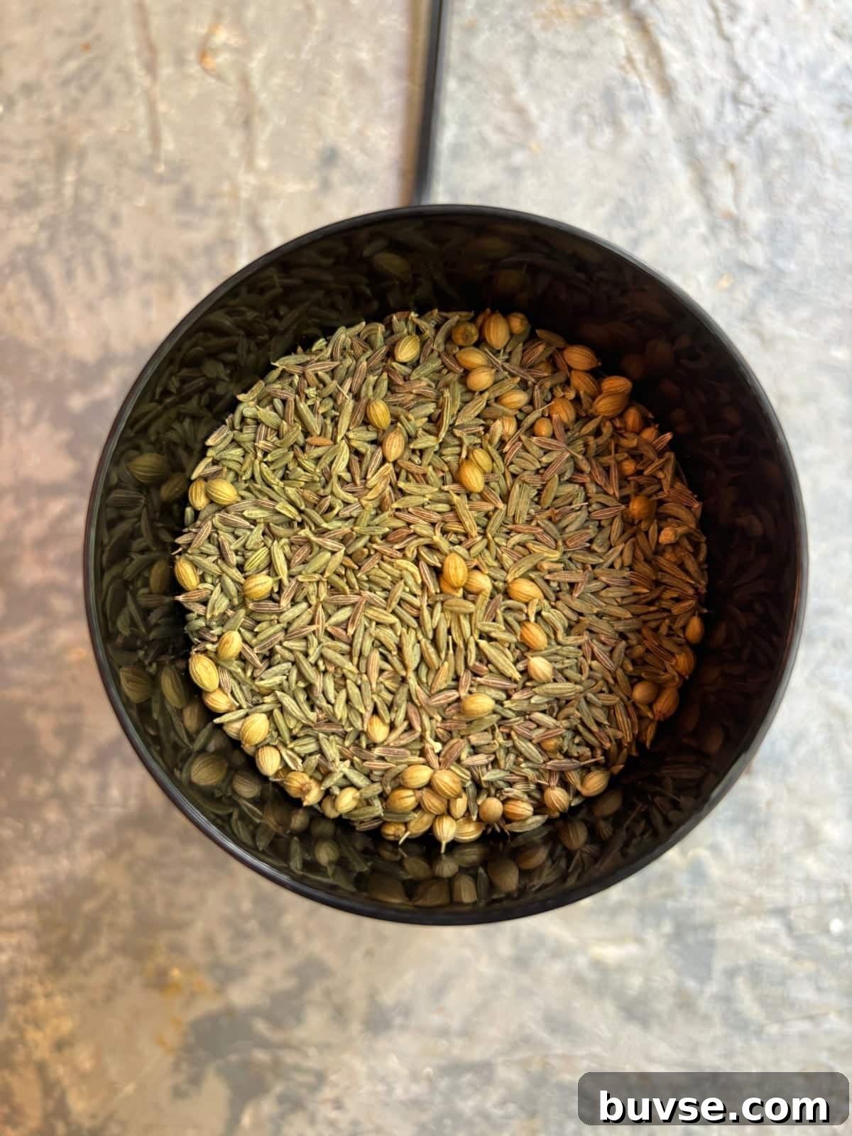 overhead image of fennel, cumin, and coriander seeds in a spice grinder