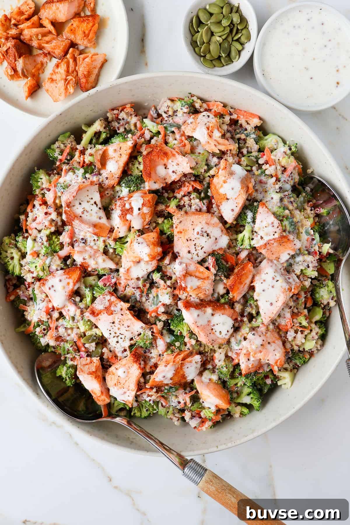 Salmon quinoa salad in a bowl with spoons.