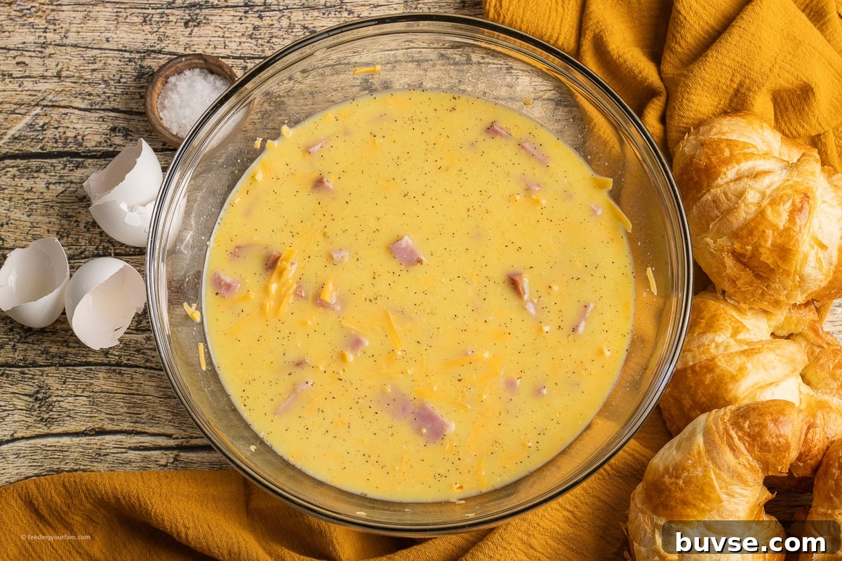 eggs, milk, cheese and ham in a mixing bowl