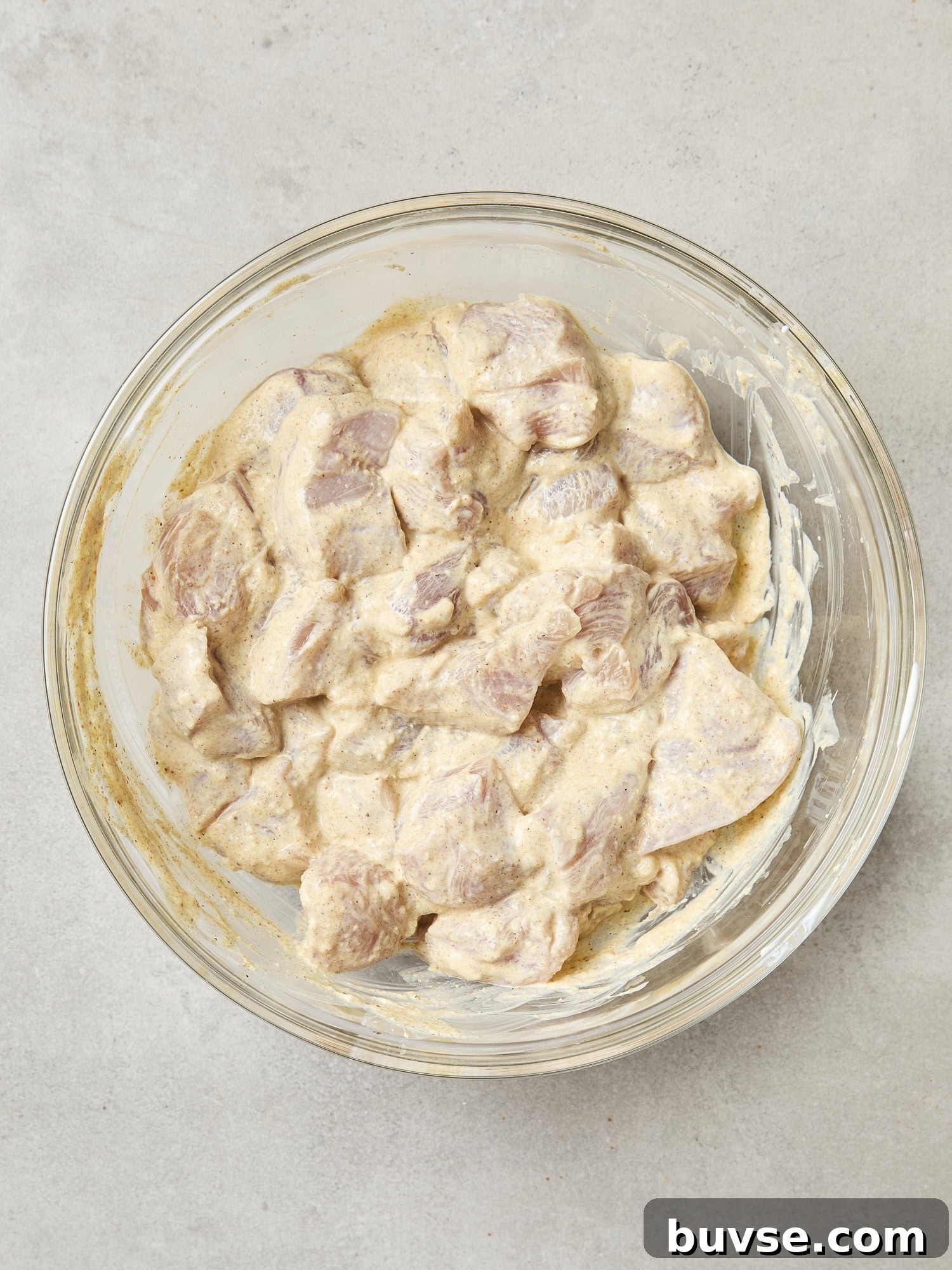 Glass bowl with marinating chicken.