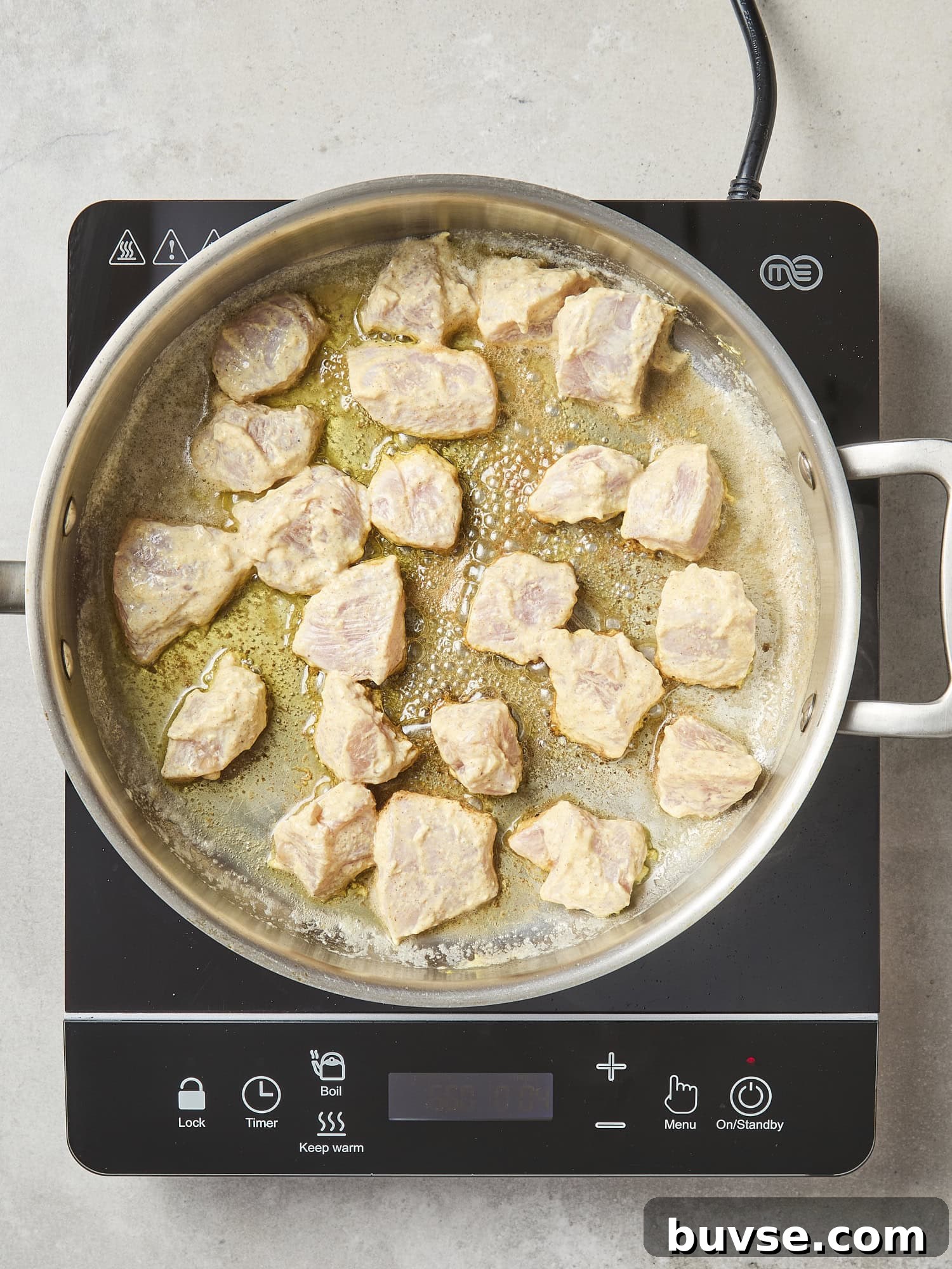 Pieces of raw chicken cooking in pan.